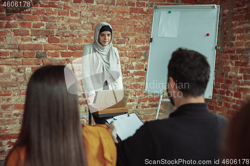 Image of Female muslim speaker giving presentation in hall at university workshop