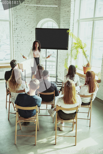 Image of Female african-american speaker giving presentation in hall at university workshop