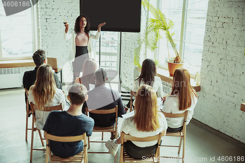 Image of Female african-american speaker giving presentation in hall at university workshop