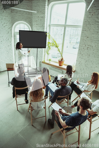 Image of Female african-american speaker giving presentation in hall at university workshop