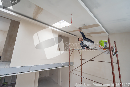 Image of construction worker plastering on gypsum ceiling