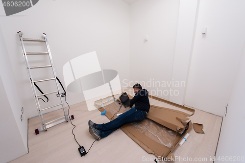 Image of man using laptop while lying on cardboard box