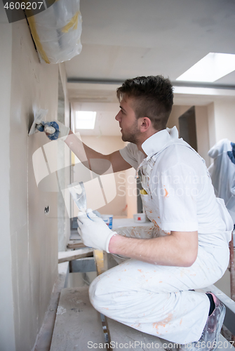 Image of construction worker plastering on gypsum walls