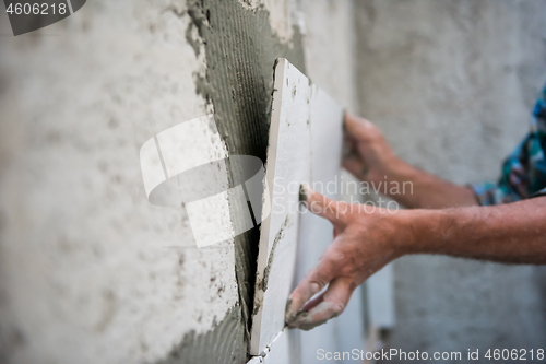 Image of worker installing big ceramic tiles