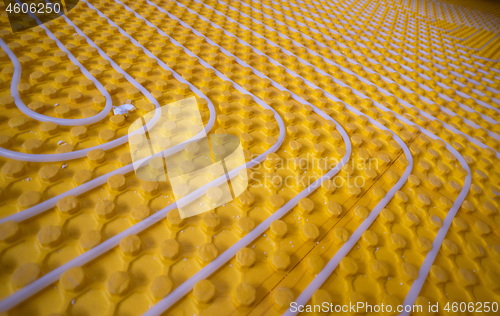 Image of yellow underfloor heating installation with white pipes