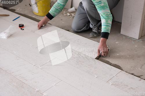 Image of worker installing the ceramic wood effect tiles on the floor