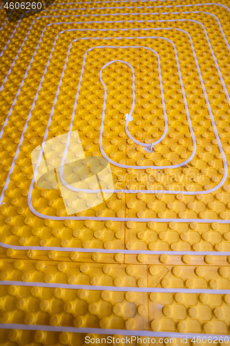 Image of yellow underfloor heating installation with white pipes