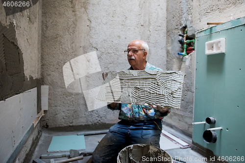 Image of worker installing big ceramic tiles