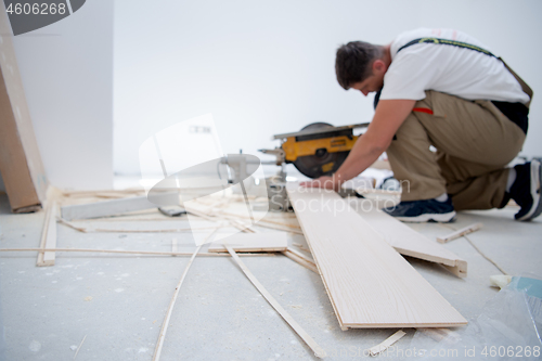 Image of Man cutting laminate floor plank with electrical circular saw