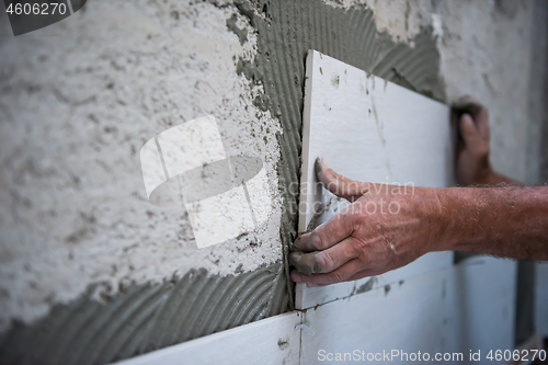 Image of worker installing big ceramic tiles