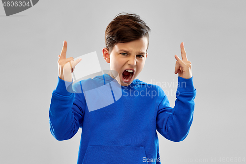 Image of angry boy in blue hoodie showing rock gesture