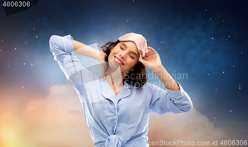 Image of happy young woman in pajama and eye sleeping mask