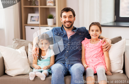 Image of happy father with daughters on sofa at home