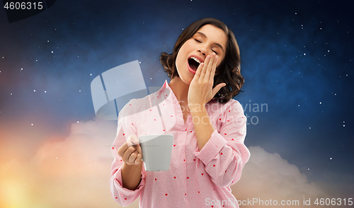 Image of happy yawning young woman in pajama with coffee