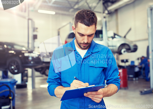 Image of auto mechanic man with clipboard at car workshop