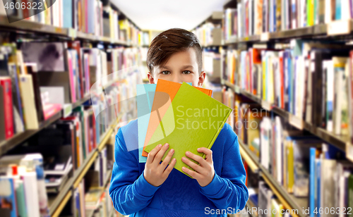 Image of shy student boy hiding behind books at library