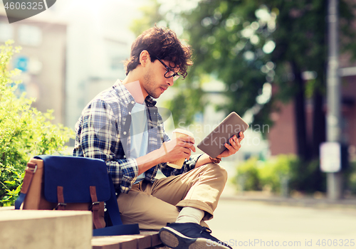 Image of man with tablet pc sitting on city street bench