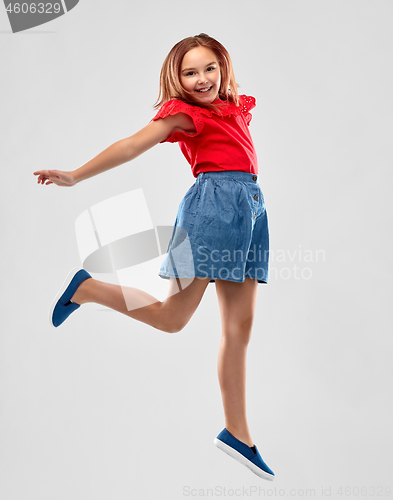 Image of happy smiling girl in red shirt and skirt jumping