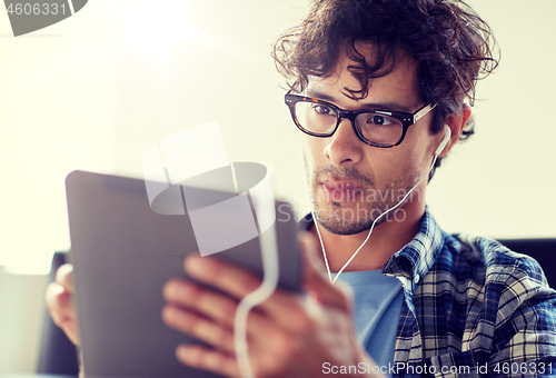 Image of man with tablet pc and earphones sitting at cafe