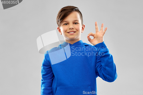 Image of boy in blue hoodie showing ok hand sign