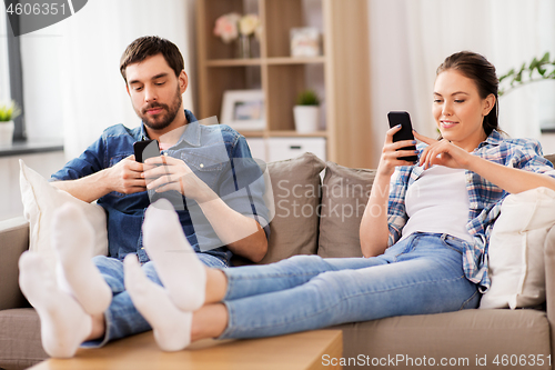 Image of couple with smartphones at home