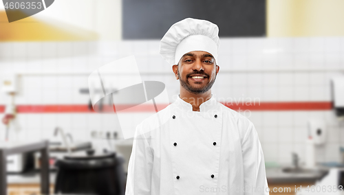 Image of happy indian chef in toque at restaurant kitchen