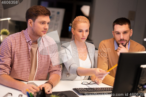 Image of business team with computer working late at office