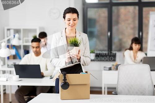 Image of happy businesswoman with personal stuff at office