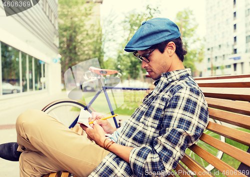 Image of man with notebook or diary writing on city street