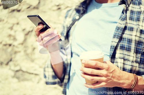 Image of man with smartphone and coffee on city street