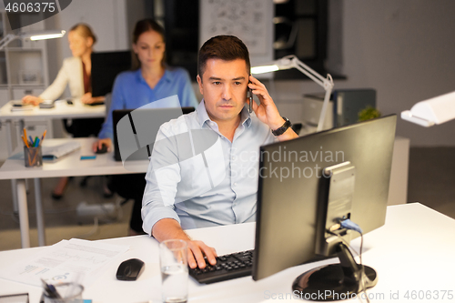 Image of man calling on smartphone at night office