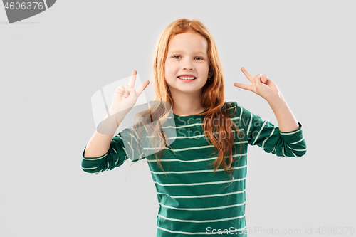 Image of smiling red haired girl showing peace gesture