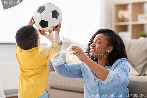 Image of mother and baby playing with soccer ball at home