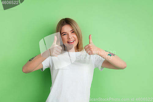 Image of Caucasian young woman\'s portrait on green studio background