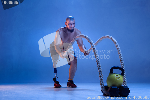 Image of Athlete disabled amputee isolated on blue studio background