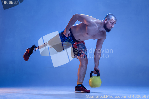 Image of Athlete disabled amputee isolated on blue studio background