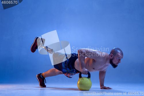 Image of Athlete disabled amputee isolated on blue studio background