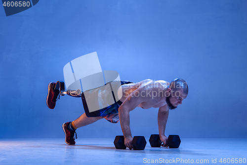 Image of Athlete disabled amputee isolated on blue studio background