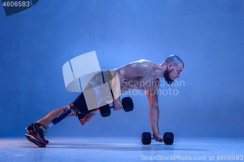 Image of Athlete disabled amputee isolated on blue studio background
