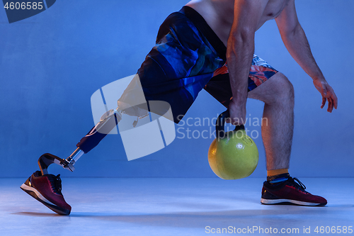 Image of Athlete disabled amputee isolated on blue studio background