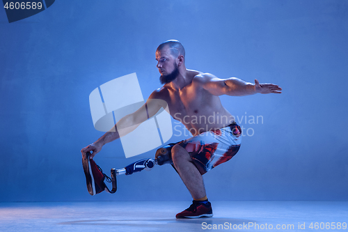 Image of Athlete disabled amputee isolated on blue studio background