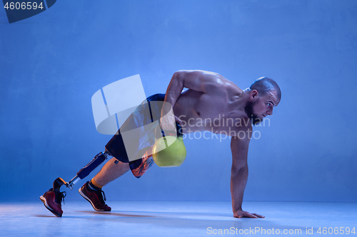 Image of Athlete disabled amputee isolated on blue studio background