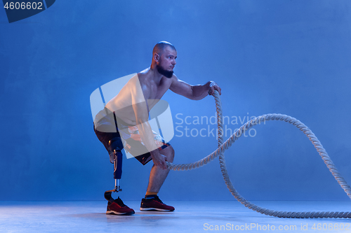 Image of Athlete disabled amputee isolated on blue studio background