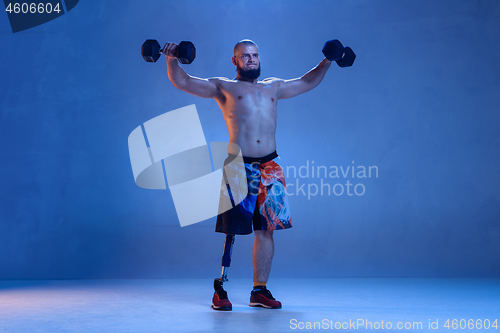 Image of Athlete disabled amputee isolated on blue studio background