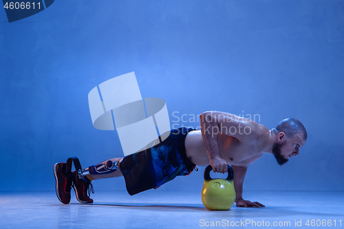 Image of Athlete disabled amputee isolated on blue studio background