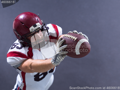 Image of american football player showing football to camera