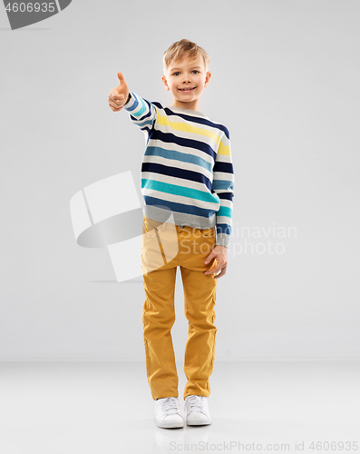 Image of smiling boy in striped pullover showing thumbs up