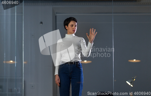 Image of businesswoman using glass wall at night office