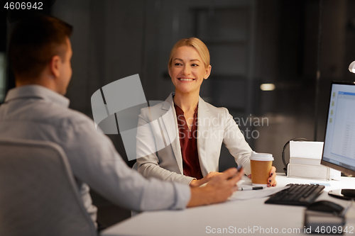 Image of business people drinking coffee at night office