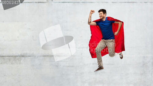 Image of man in red superhero cape jumping over concrete